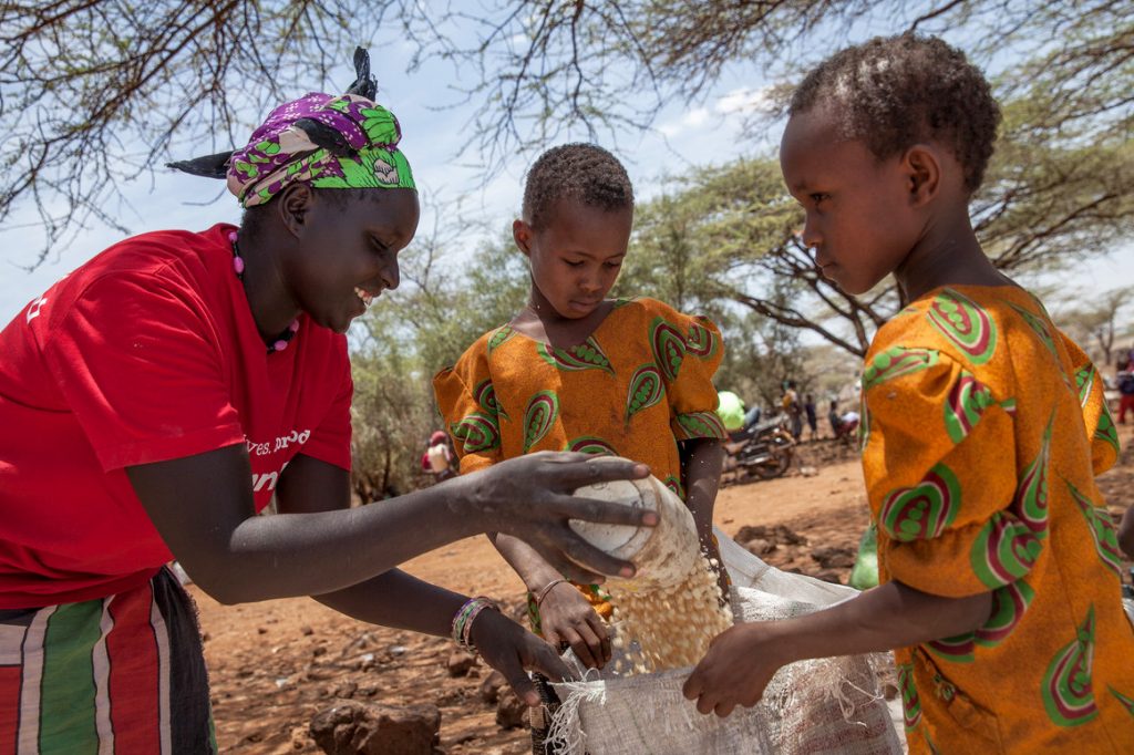 A female ActionAid staff member distributes food to two young sisters in Kenya as part of ActionAid's response to the food crisis in East Africa.