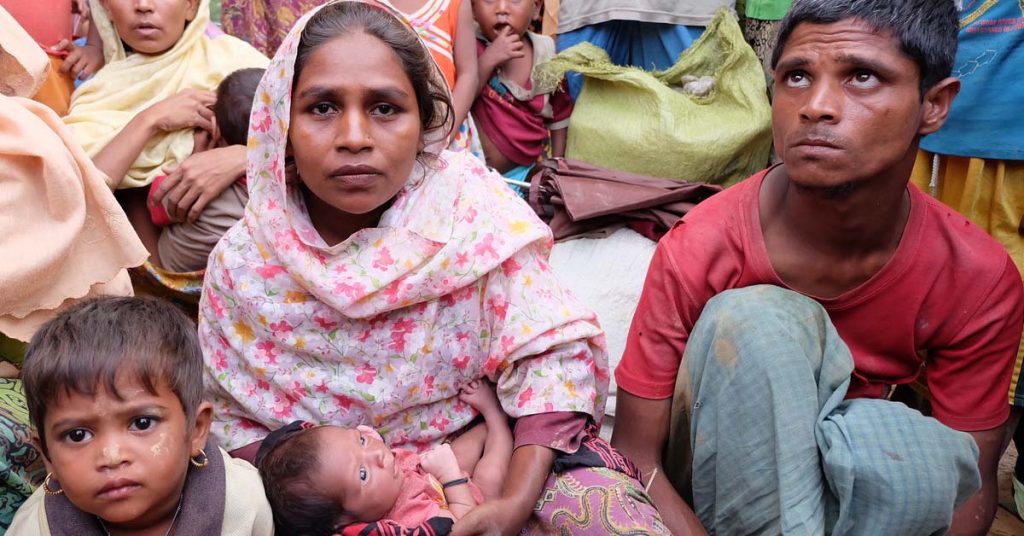 Ambia Khatun holds her young child and sits between her toddler and partner.