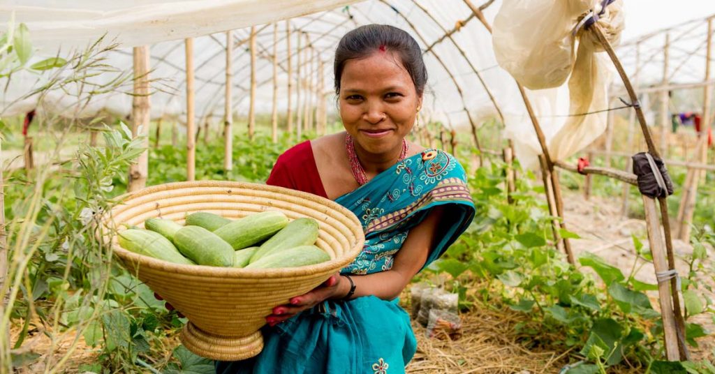 A woman in Nepal holds a basket of fresh vegetables.