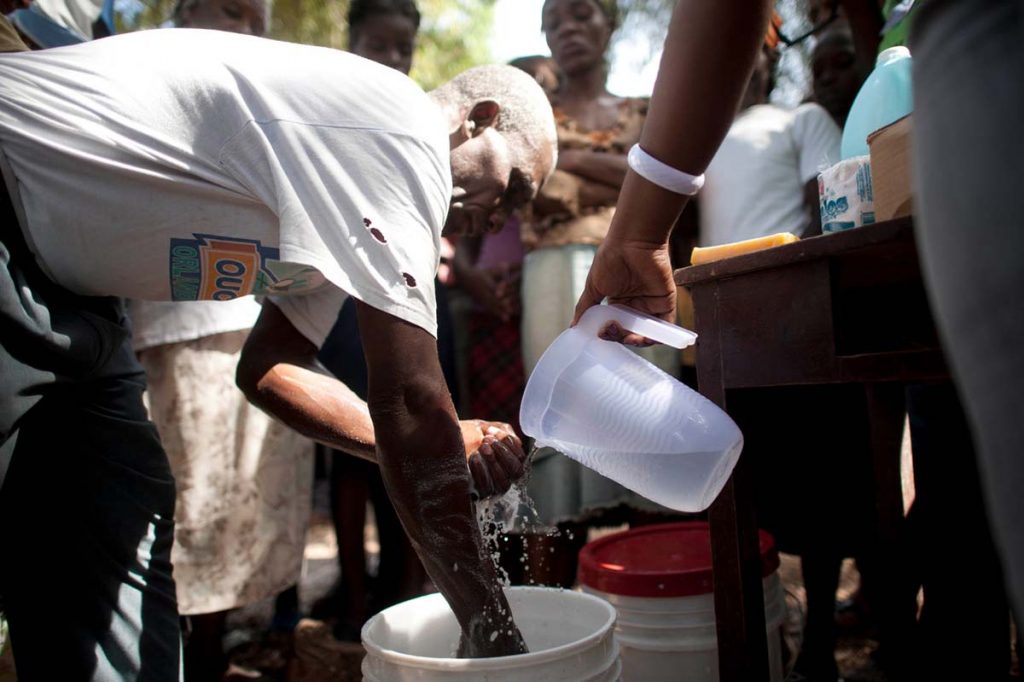 A man in Haiti washes his hands in a bucket.