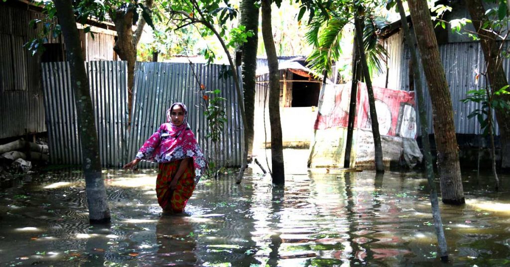 A woman walks in knee-high water after mass flooding in Bangladesh.