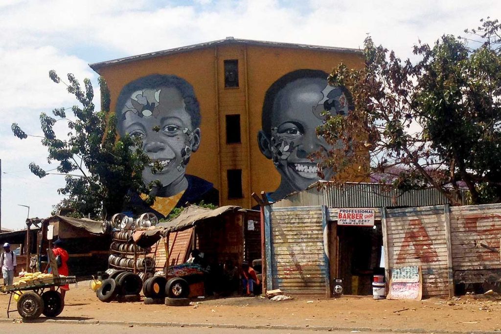 A wall mural in Zimbabwe features the smiling faces of two children.