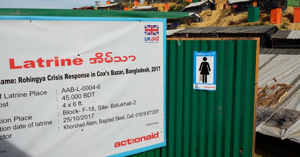 A green structure with a large sign that reads: "Latrine" and features ActionAid's logo. A sign next to it indicates that the bathroom is for female use. ActionAid Bangladesh built this to address concerns of safety among Rohingya women in the refugee camp.