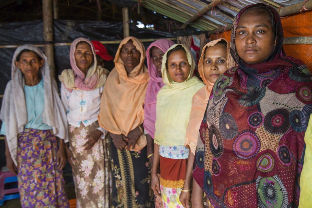 Seven women stand side by side in a temporary shelter in a camp for Rohingya refugees in Cox's Bazar, Bangladesh.
