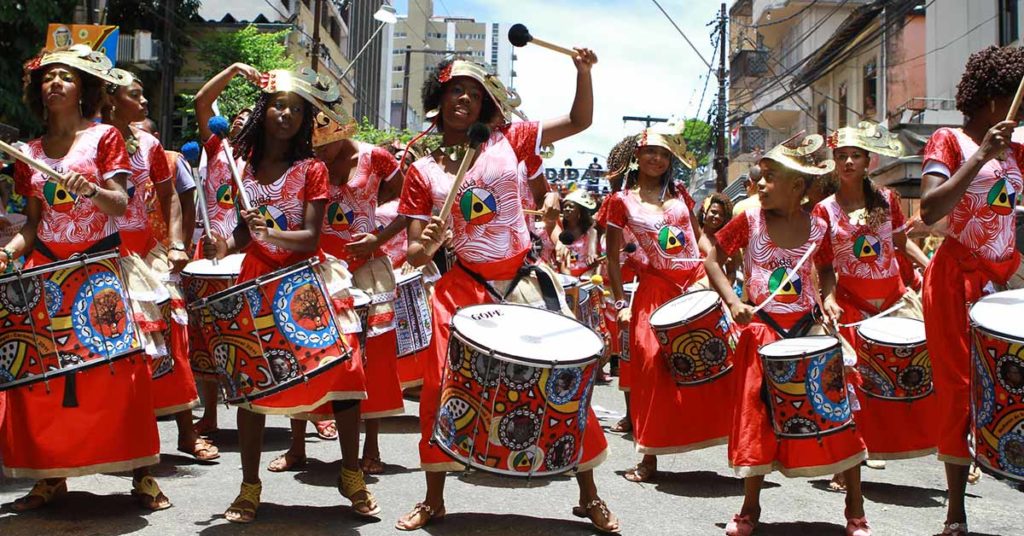 A group of female Afro-Brazilian drummers dressed in red perform in the streets of Brazil.
