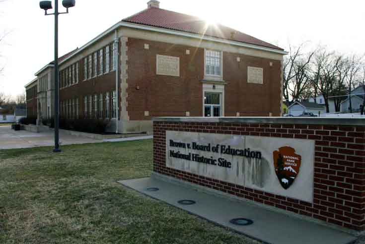 A brick sign with the words Brown v Board of Education National Historic Site and a brick building it, commemorating the historic case desegregation public schools. Linda Brown was the symbol of this case.