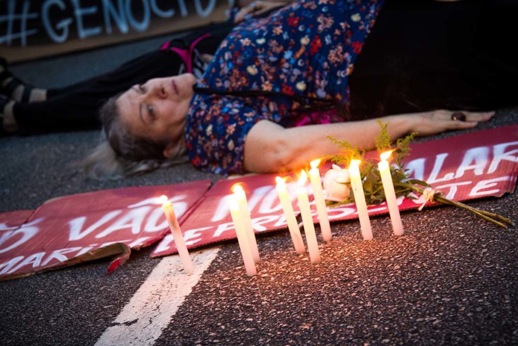 A woman lies on pavement with lit candlesticks beside her to mourn the assassination of Marielle Franco in Rio de Janerio, Brazil.