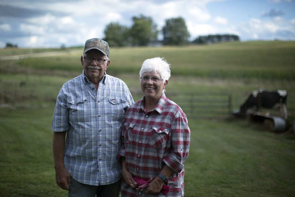 A man and a woman stand next to each other on a grassy field. Family farmers like them need a farm bill that supports their livelihood.