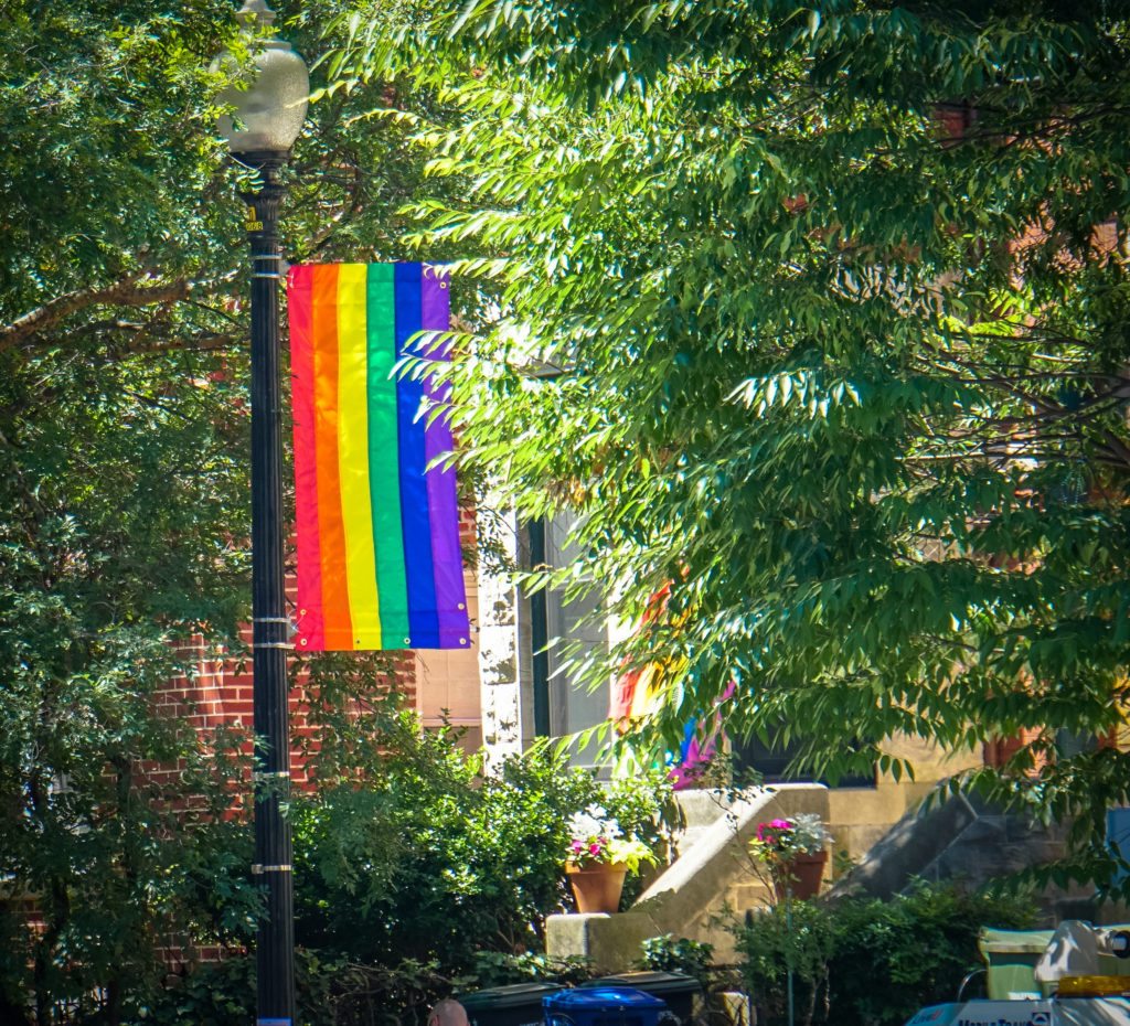 A rainbow flag hanging in front of a house.