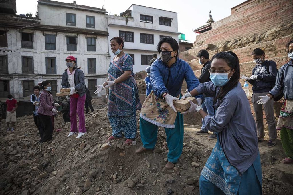 Female volunteers in a line pass bricks from ancient buildings destroyed in the 2015 Nepal Earthquake.