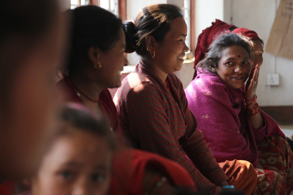 Five women and a girl are sitting in a row, laughing.