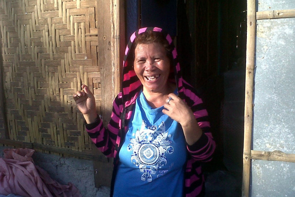 A 50-year-old Filipina woman smiles in the doorway of a local school where she stayed after Typhoon Haiyan destroyed her house in 2013.