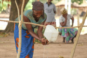 Ningo community member, Asibi, demonstrates how to set up the improvised tap that has been replicated in all households in her community