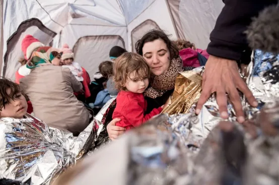 Women change themselves and their kids into dry clothes in a tent set up by ActionAid on a beach in Lesvos. Photo: Karin Schermbrucker/ActionAid