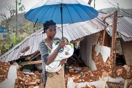 Josie and her son Jerry in front of the remains of their house. Photo: Dylan Roberts/FreeSociety/ActionAid
