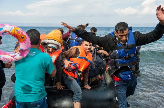 People leap from a small boat that has just arrived in Lesvos, Greece. Photo: George Makkas/Panos Pictures/ActionAid
